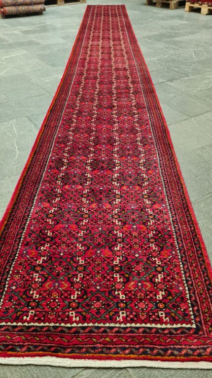 Close-up of a traditional hand-knotted Persian Hamadan rug with geometric medallion design in deep red and blue